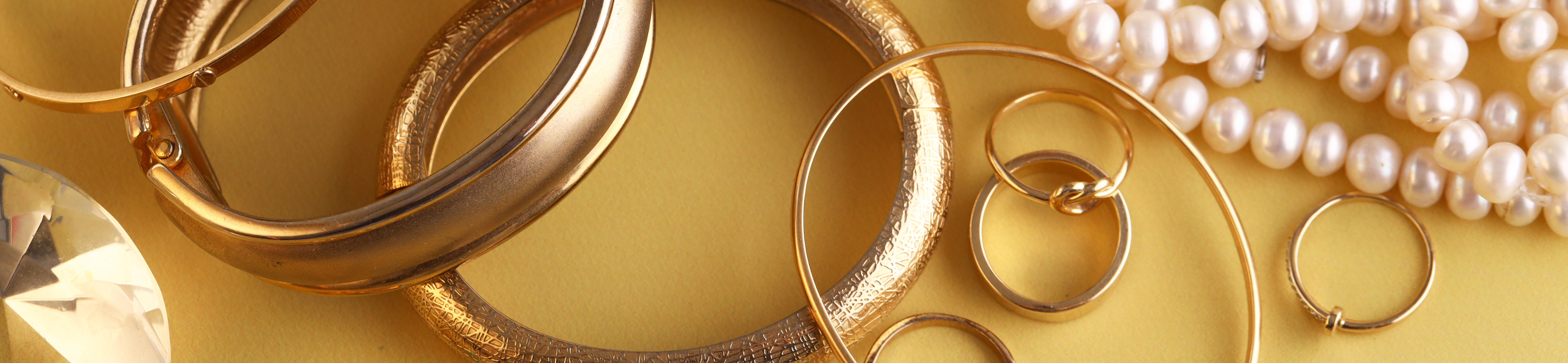 Various Precious Metals on Yellow Background, Bracelets, Rings, Pearl Necklace
