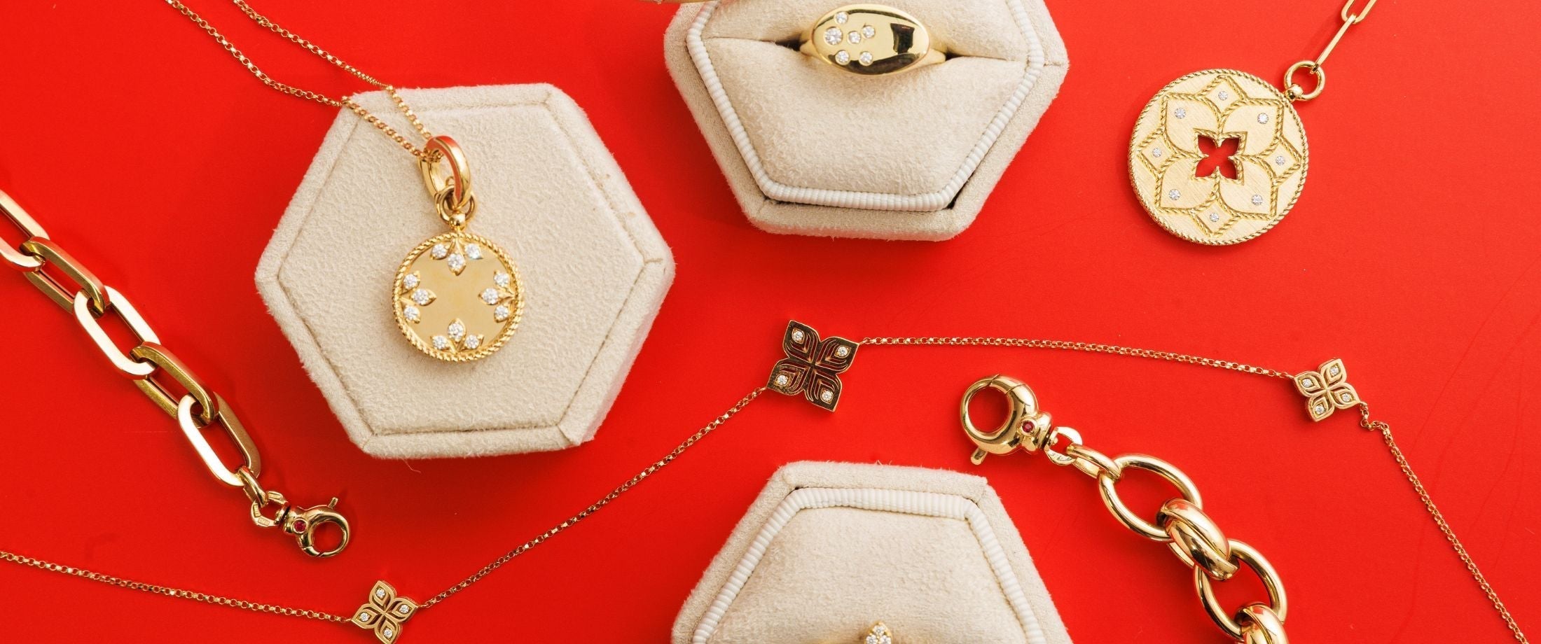 roberto-coin-red-background-yellow-gold-jewelry-flat-lay